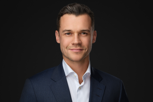 Professional corporate headshot of a man in a navy suit on a dark studio background, photographed in Montreal.
