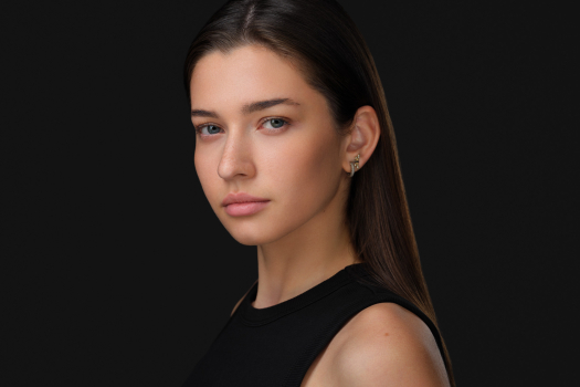 Studio headshot of a young woman in black against a dark background by Montreal photographer Vadim Daniel