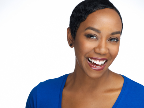 Professional business headshot of a smiling woman in a blue top on a light studio background, photographed in Montreal.