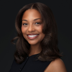 Professional corporate headshot of a smiling woman in a black top on a dark studio background by Montreal photographer Vadim Daniel