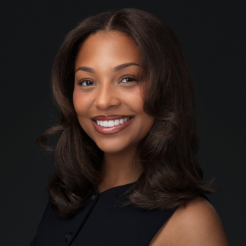 Professional corporate headshot of a smiling woman in a black top on a dark studio background by Montreal photographer Vadim Daniel